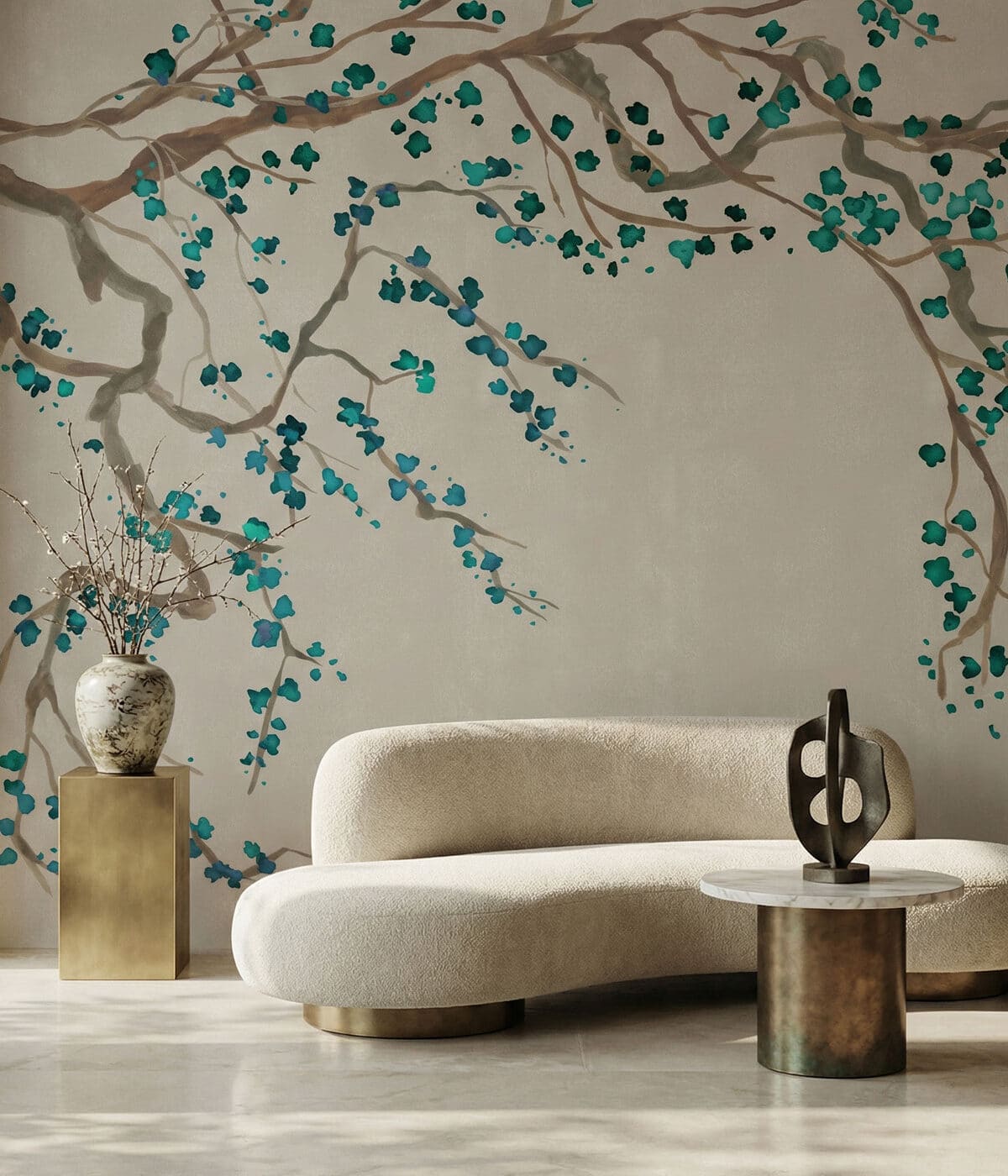 A refined living space featuring a cream wall mural with sweeping branches adorned in vibrant teal blossoms. A curved ivory boucle sofa with a brass base anchors the room, paired with a sculptural bronze side table topped with marble and an abstract art piece. A tall brass pedestal with a ceramic vase and delicate branches complements the serene, contemporary aesthetic with subtle Asian-inspired elegance.